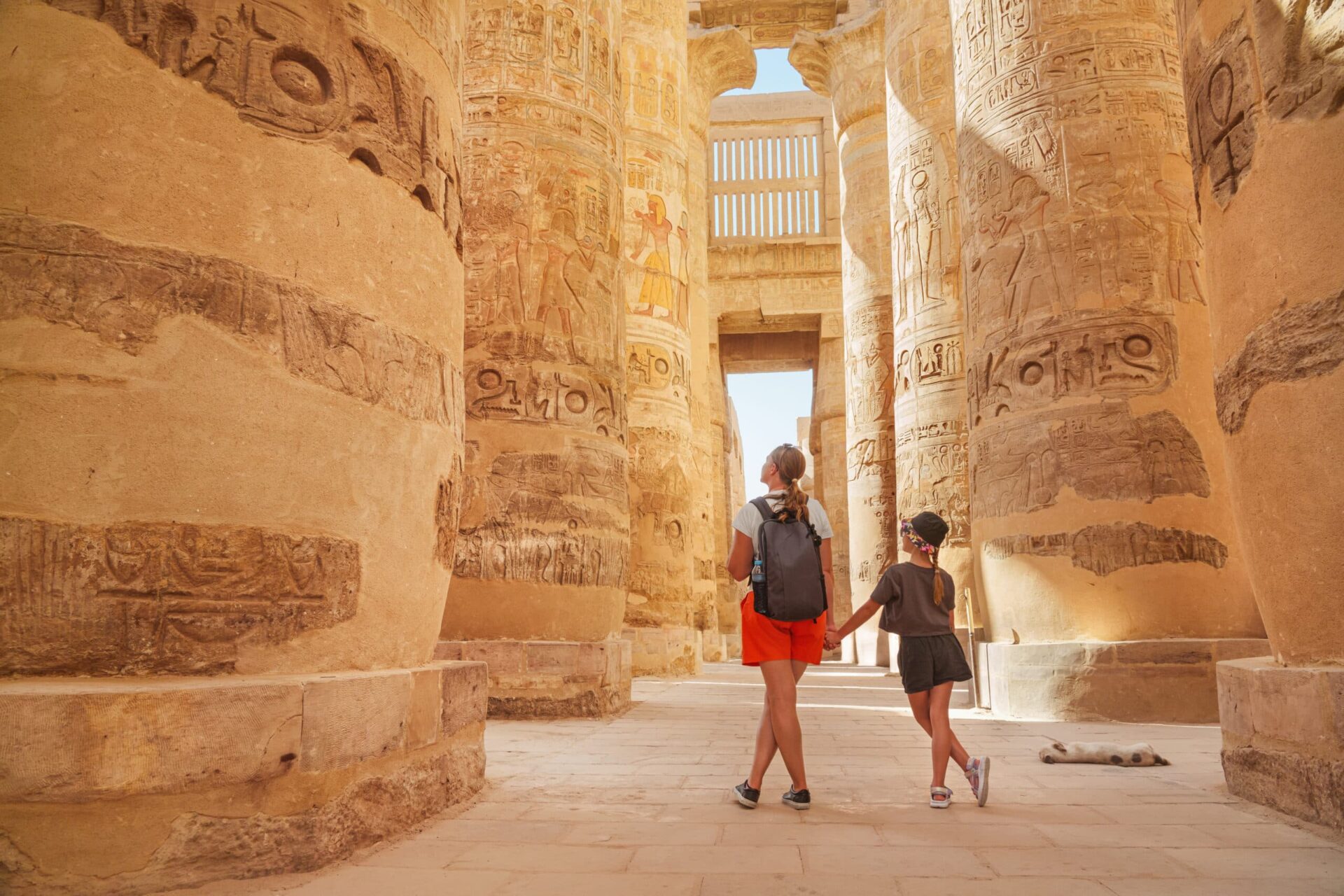Egypt - karnak hypostyle hall columns in the temple at luxor thebes and happy tourist girls - mother and daughter on vacation.